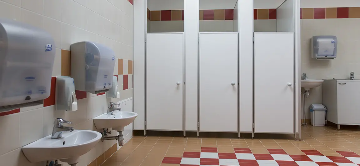 A typical school bathroom with three stalls and three sinks.