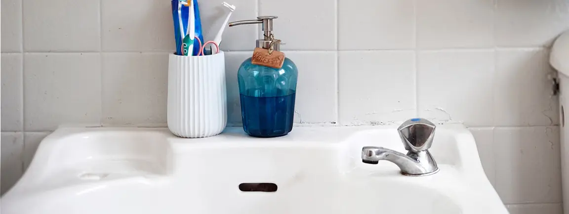 Bathroom sink with liquid soap and toothbrushes