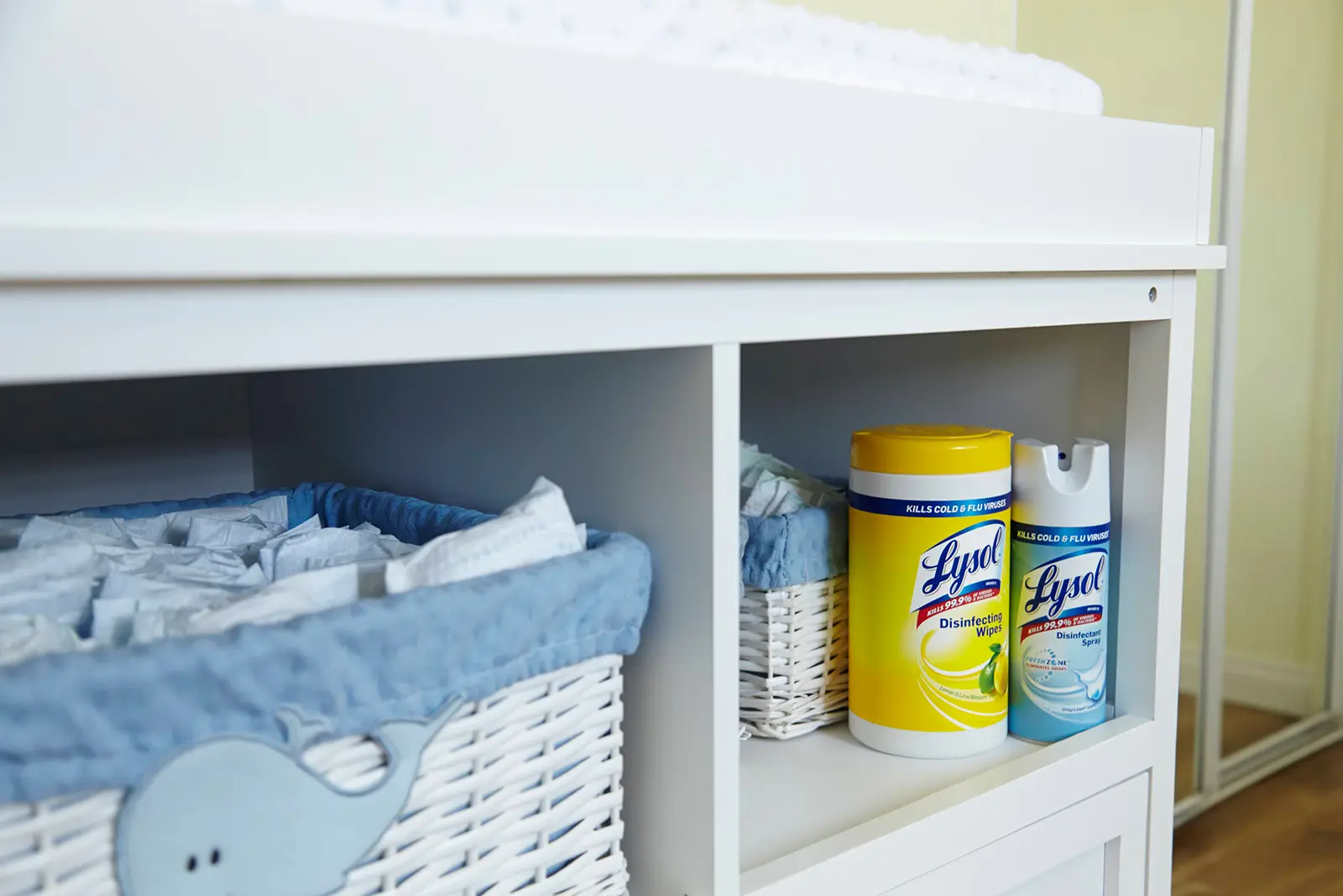 Cabinet with baskets containing diapers and canisters of Lysol Disinfecting Wipes and Lysol Disinfectant Spray