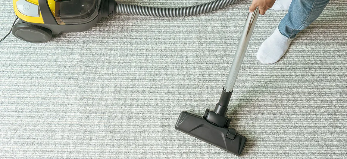 A vacuum being used on a living room carpet.