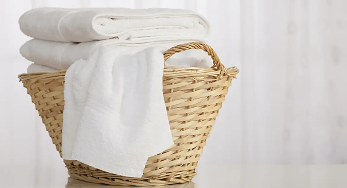 Straw laundry basked filled with clean white towels