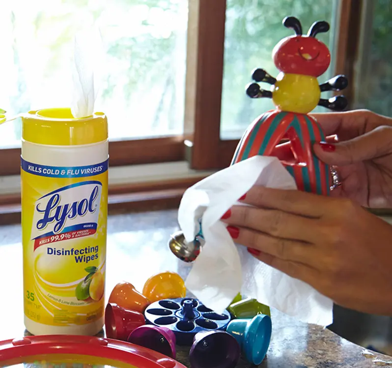 Hands using Lysol Disinfecting Wipes to clean and disinfect baby toys.