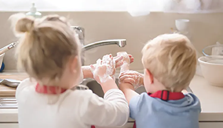Young children lathering hands with soap at a sink