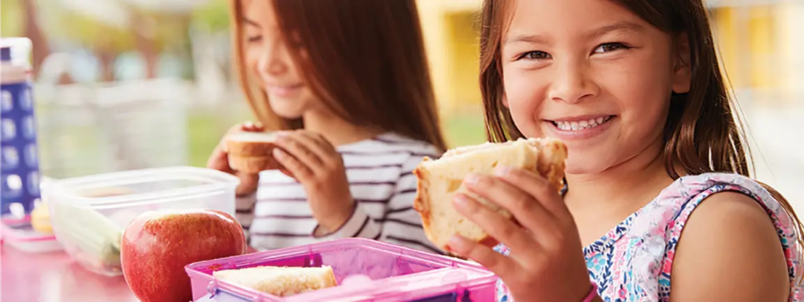 Children holding up sandwiches and smiling