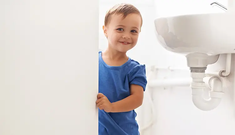 Child peering around bathroom door