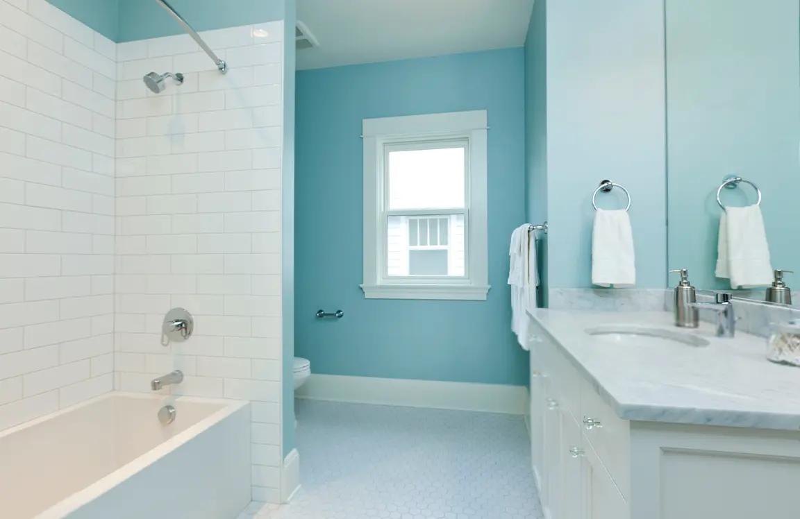 A clean modern bathroom with alcoves for a bath-shower and a toilet.