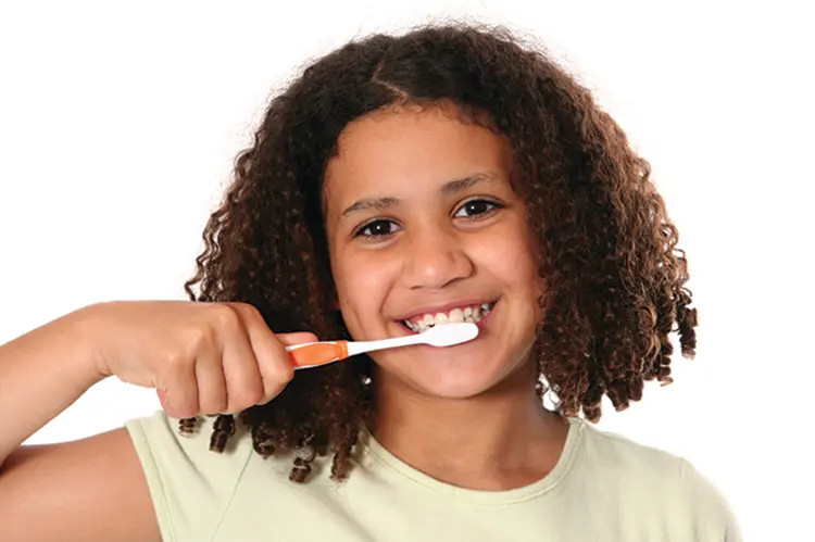 Child smiling while brushing teeth