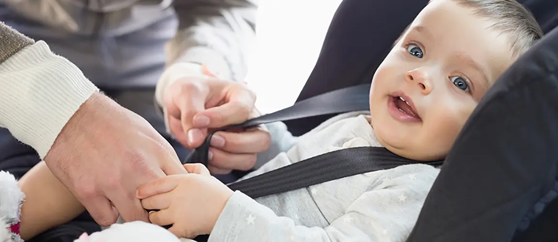 Parent straps baby into carseat