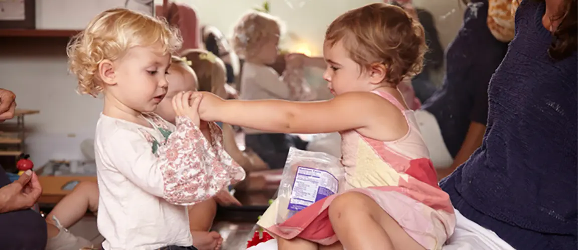 Child holds another child's hands close to their face