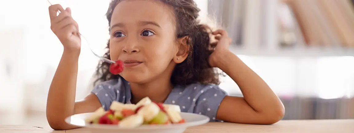 Child eating a plate of fruit