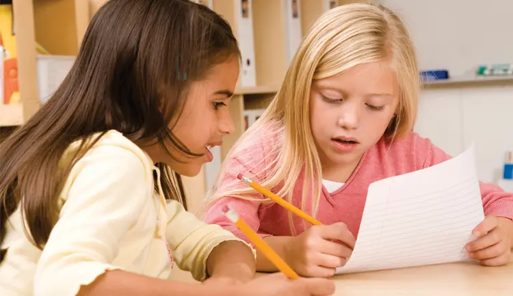 Children talking and writing on paper with pencils