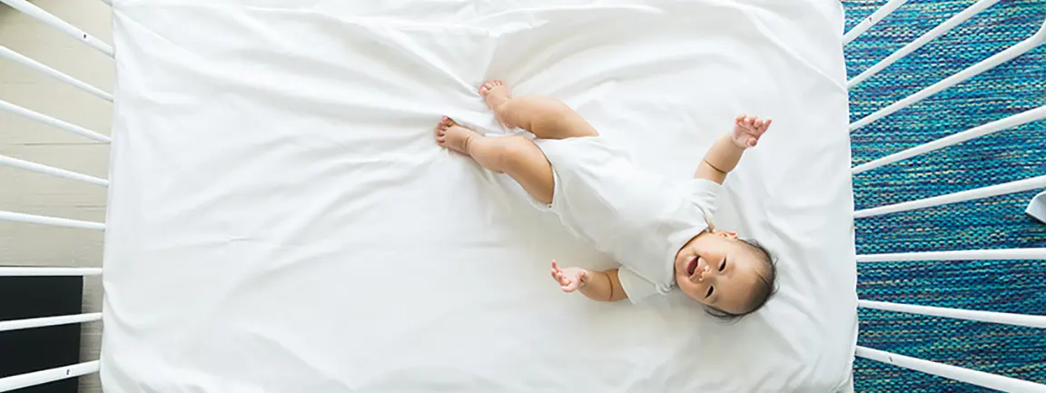 Baby lying on mattress inside crib