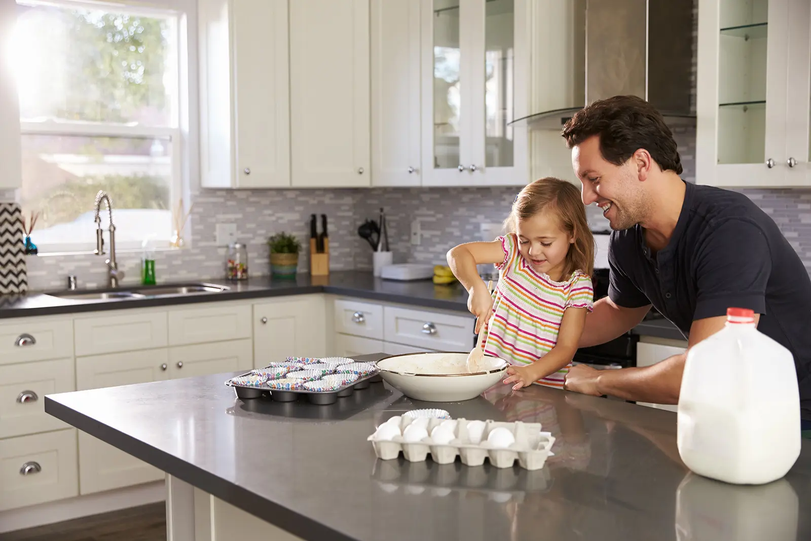 Child and parent making cupcakes on a kitchen counter