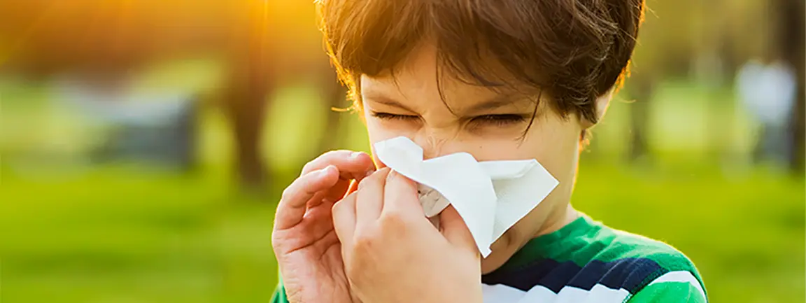 Child in garden blowing nose into tissue