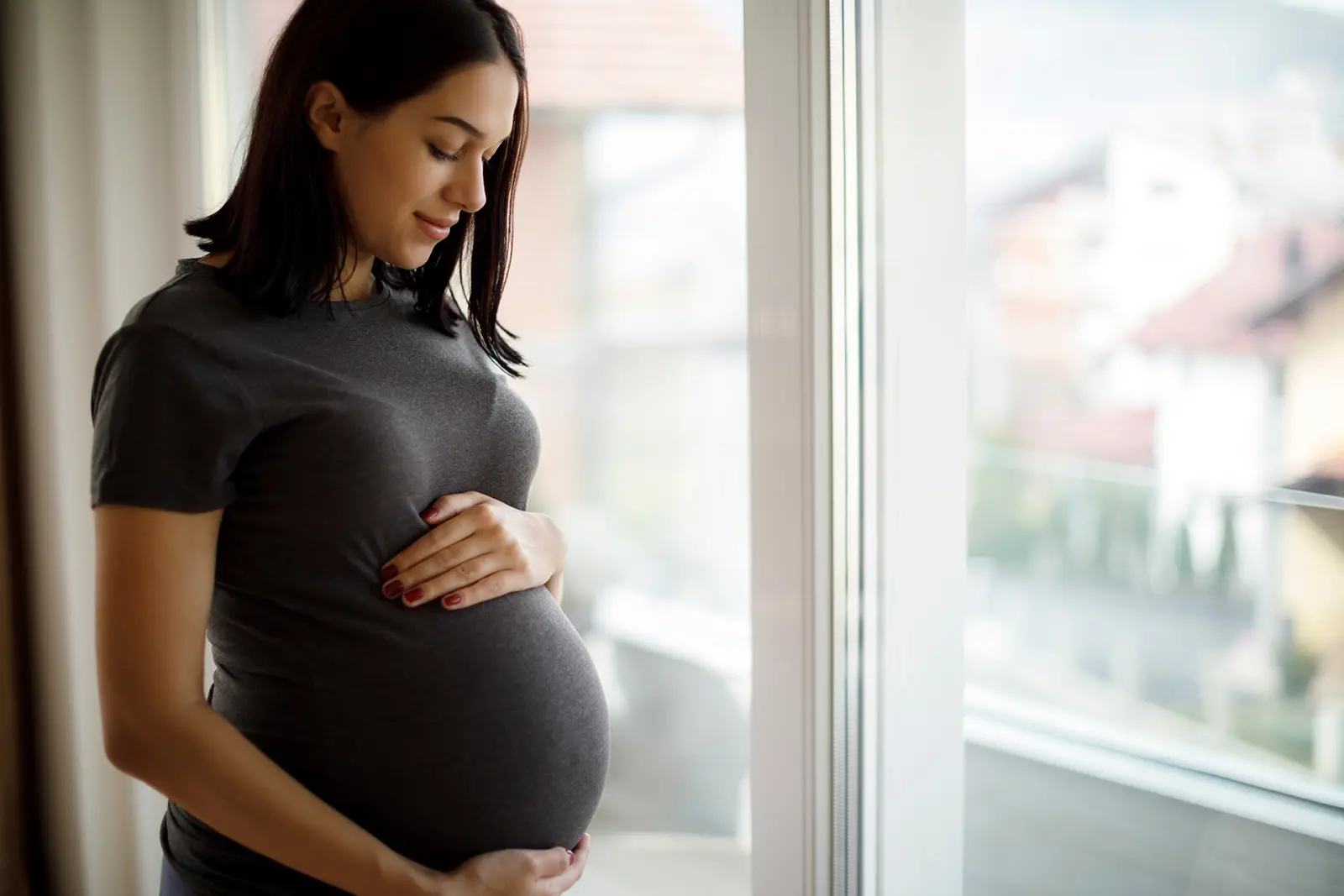 Pregnant woman staring lovingly at baby bump she is holding