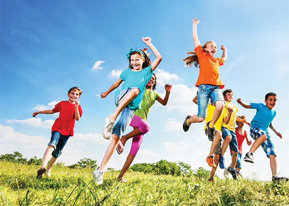 Children in colorful clothing running and jumping in a grass field