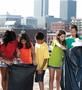Group of children holding large black garbage bags outside