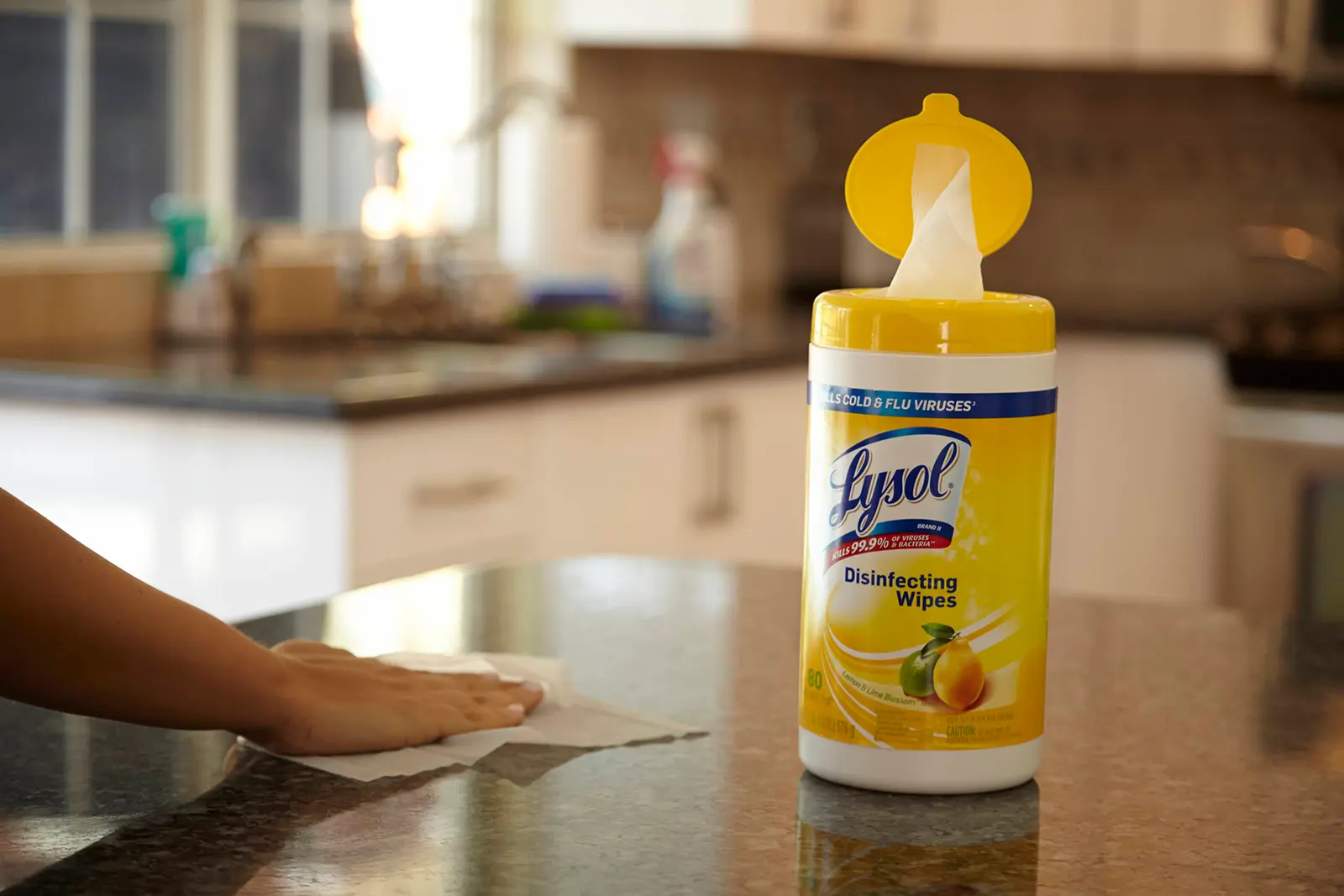 Hand wiping kitchen counted next to canister of Lysol Disinfecting Wipes