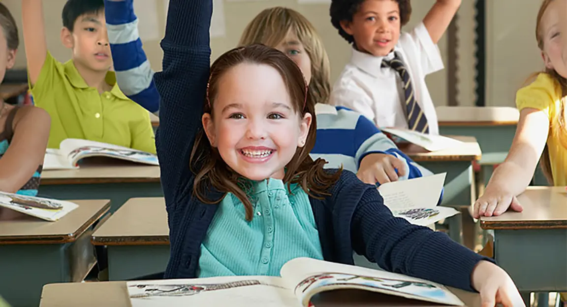 Child smiling and raising hand in classroom