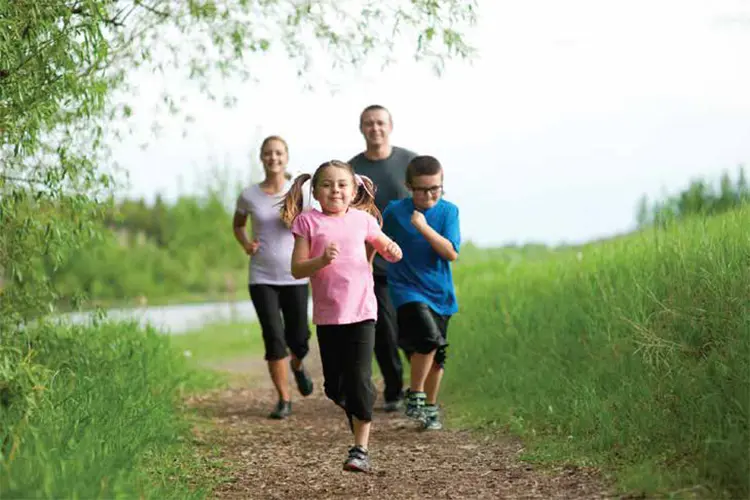Family in sportswear running on path near river