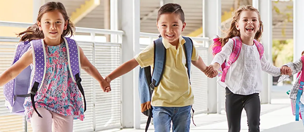 Chain of children holding hands and skipping towards camera