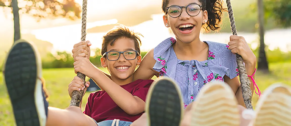 Two children smiling on garden swing