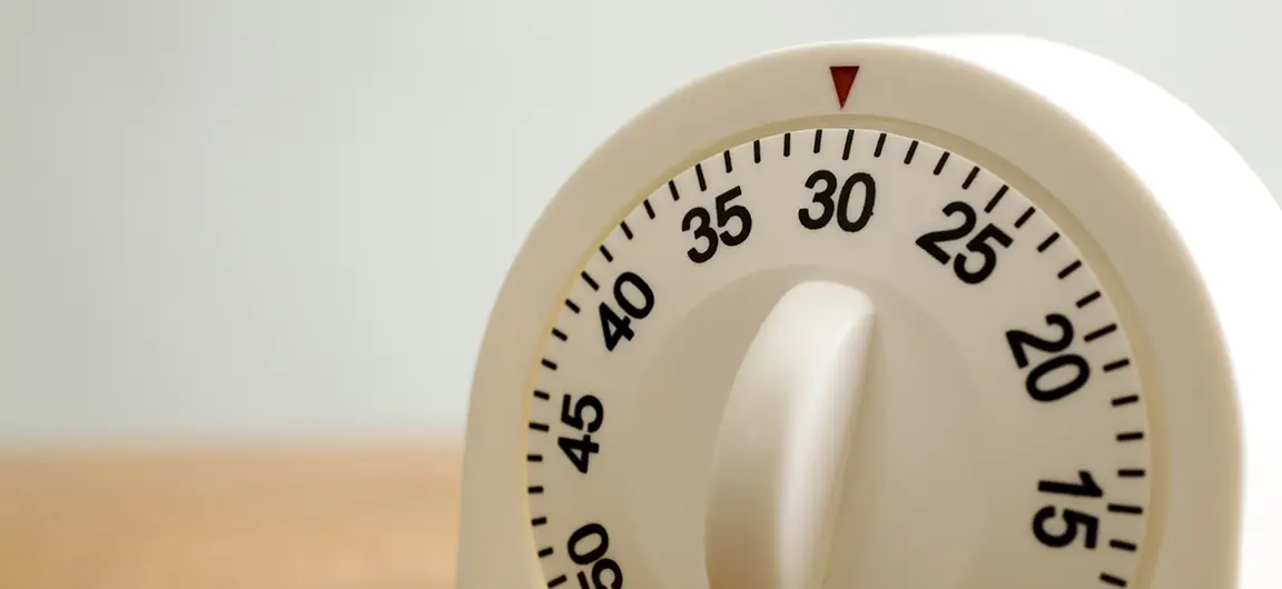 A kitchen timer on a wooden counter set to 30 minutes.