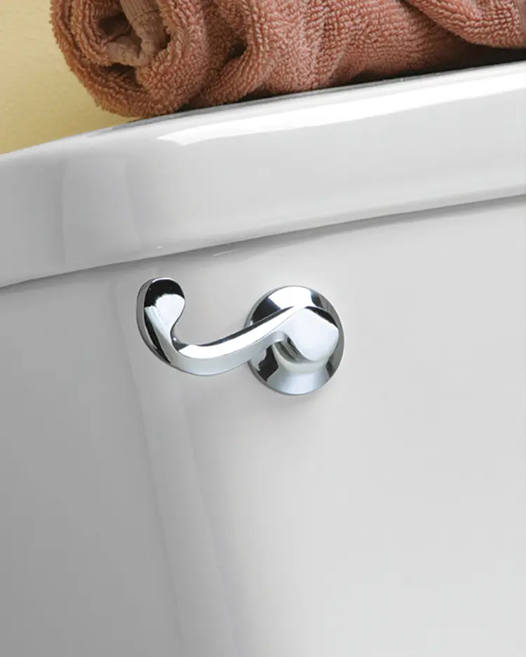 Toilet with rolled up towel on top and chrome flush handle