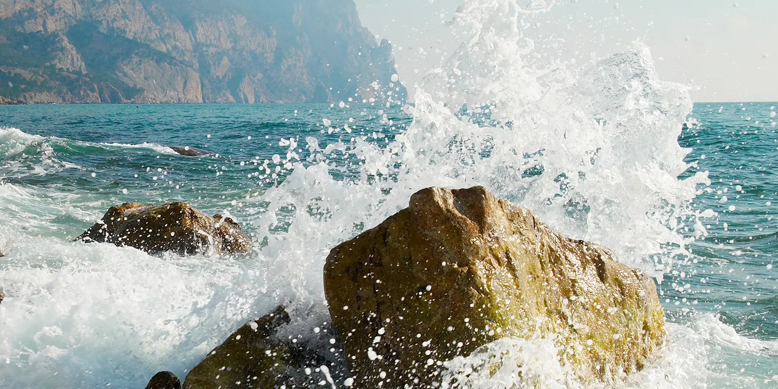 Ocean waves pounding a rock causing spray and foam