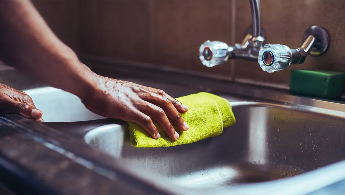 Person wiping sink with a clothe