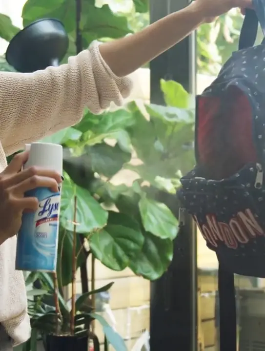 Person spraying Lysol Disinfectant Spray on a backpack