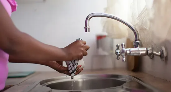 Person rinsing out cloth over stainless steel kitchen sink