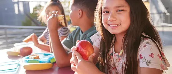 Child holding an apple and smiling at the camera