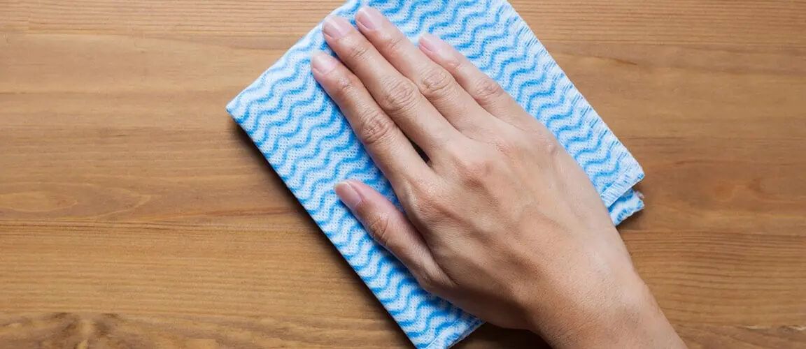 Hand wiping cloth over hard wood surface