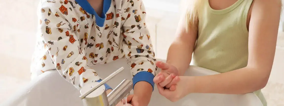 Torsos of two children holding washing hands in running bathroom sink