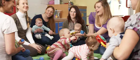Group of parents sitting in a circle on floor with toddlers on their laps