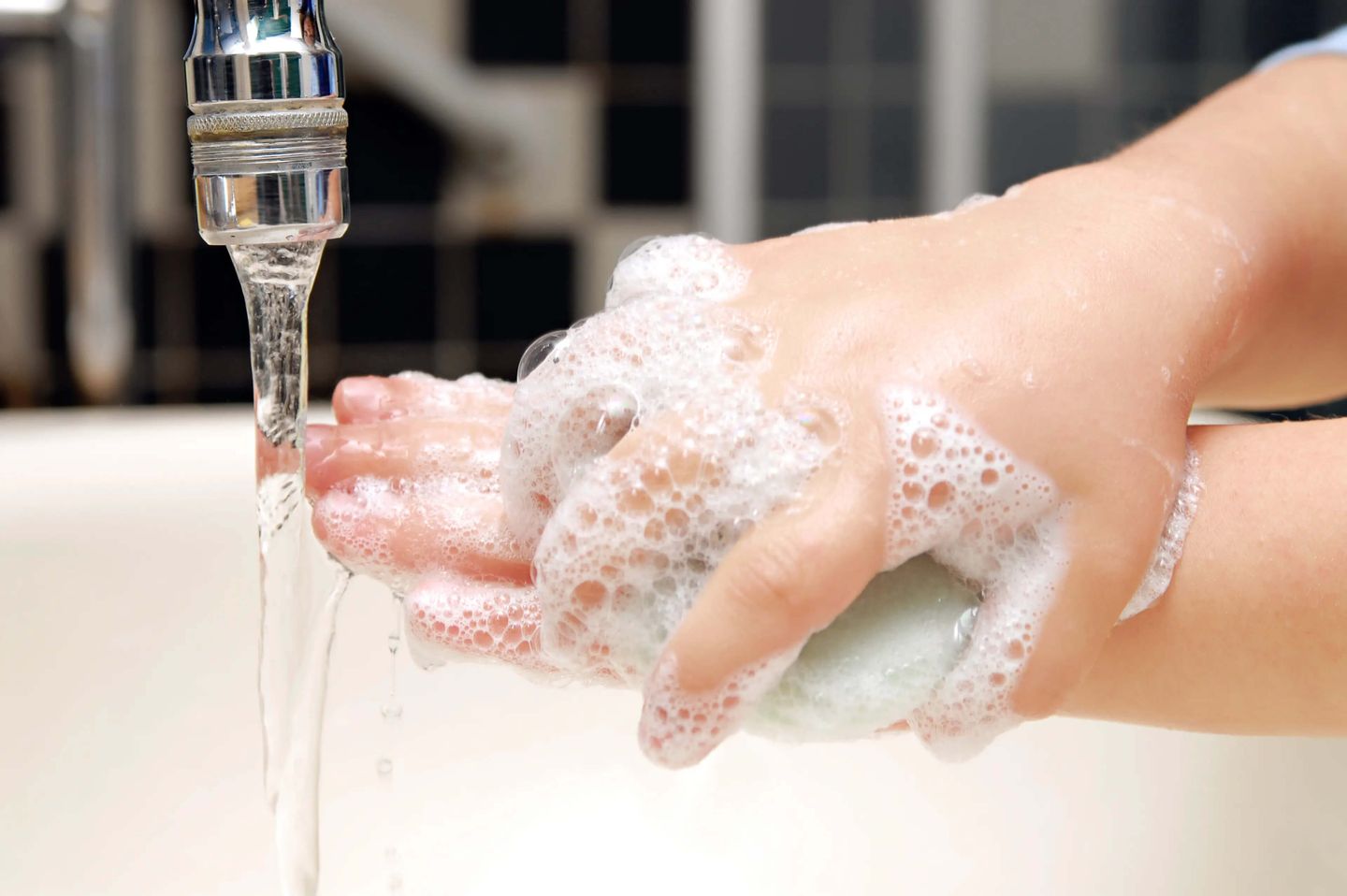 Child using a block of soap to wash hands
