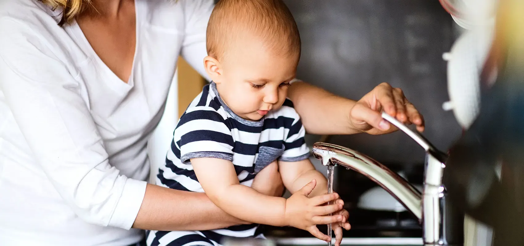 Parent helping baby to wash hands