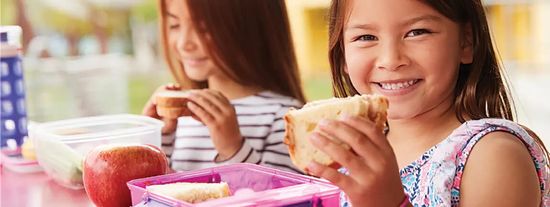 Children holding up sandwiches and smiling