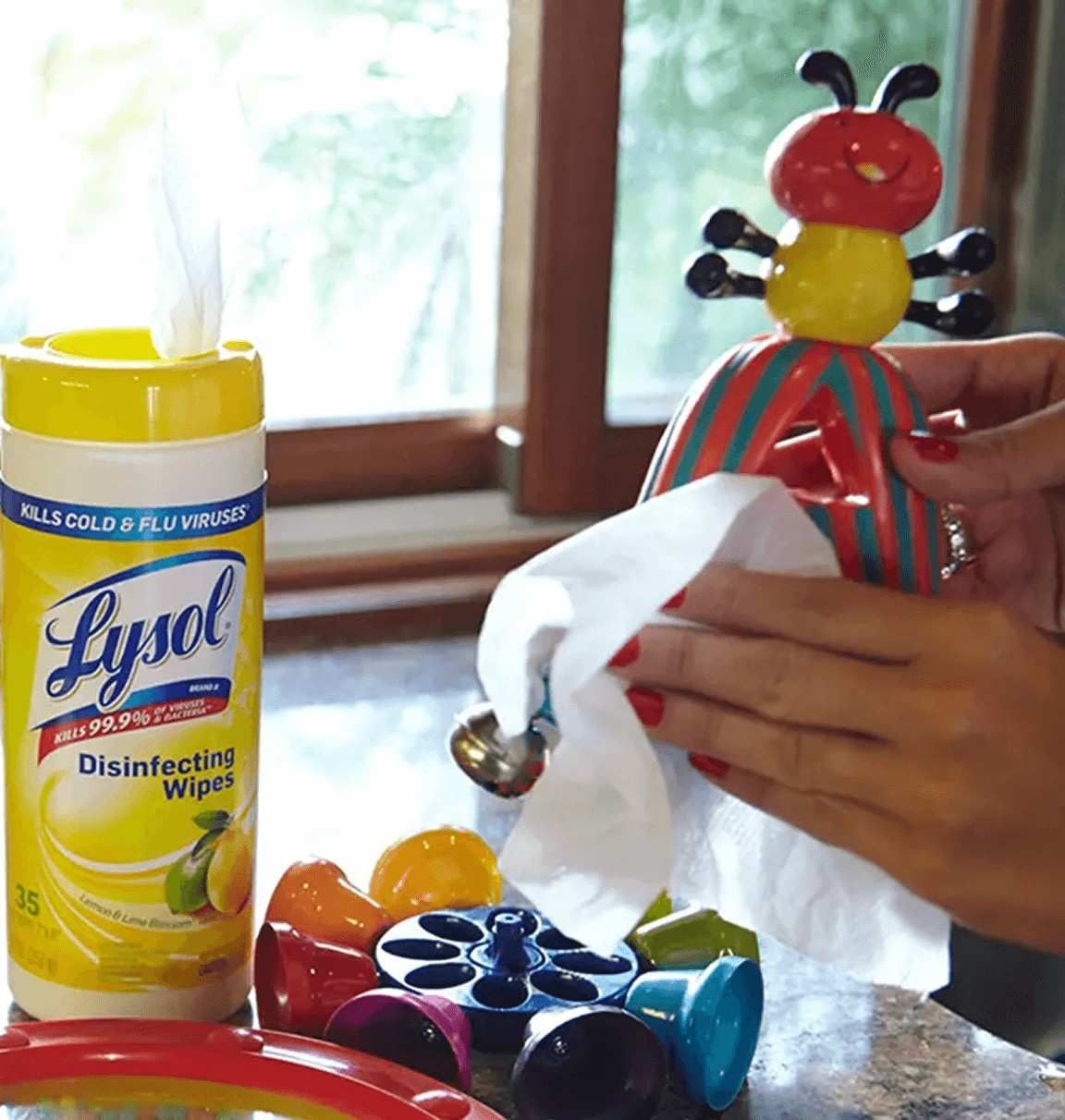 Hands using Lysol Disinfecting Wipes to clean and disinfect baby toys.