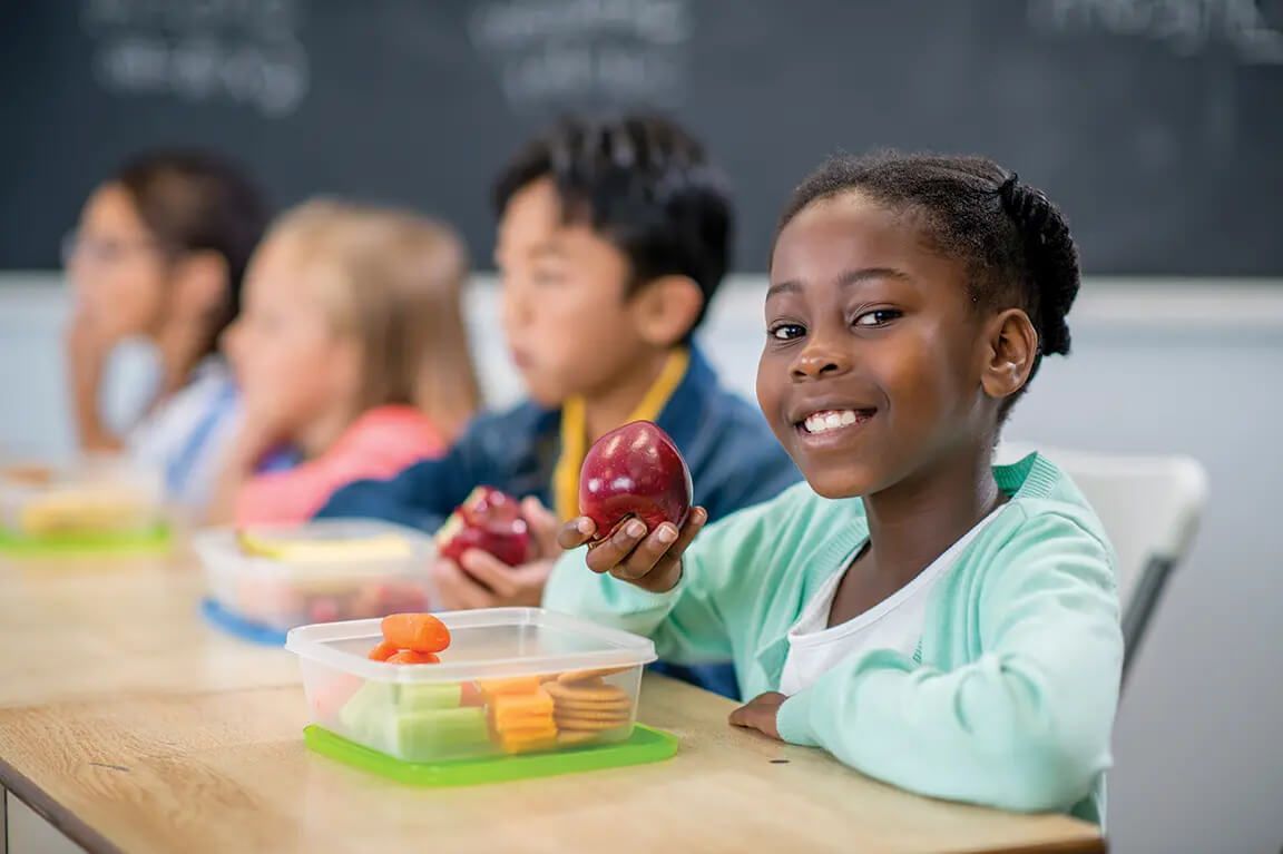 Child smiling at camera and holding apple